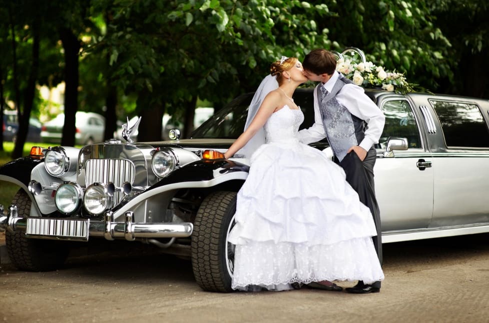 wedding couple kissing outside of a vintage car